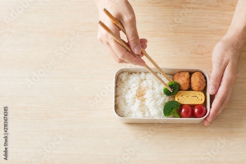 Obraz na płótnie 唐揚げと卵焼きを手作り弁当に詰める女性の手元