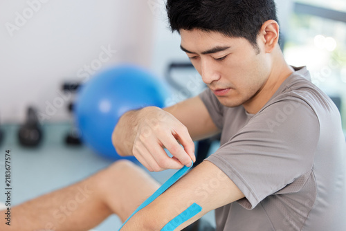 Fotografie Man Applying Athletic Tape to Shoulder for Recovery