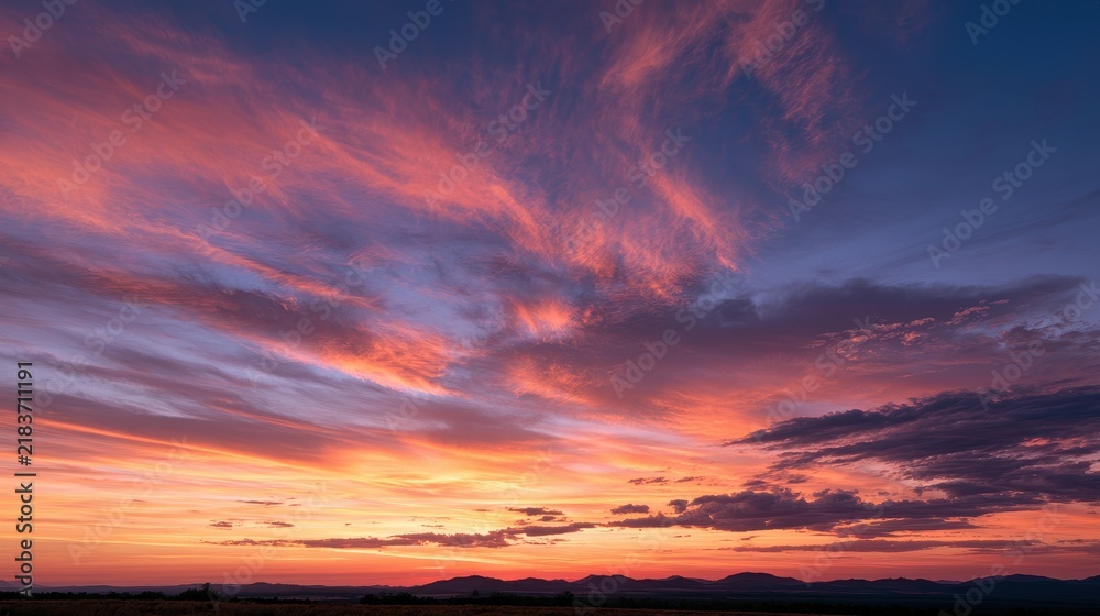Fototapeta premium Twilight sky with high-contrast colors and dramatic cloud textures over distant silhouettes