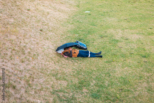 Konstfotografi A person is lying on their side on a grassy field with a makeshift shelter above them