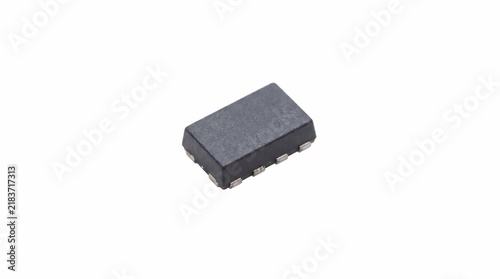 Small integrated circuit chip with black plastic housing and metal pins isolated against a plain white studio background surface area