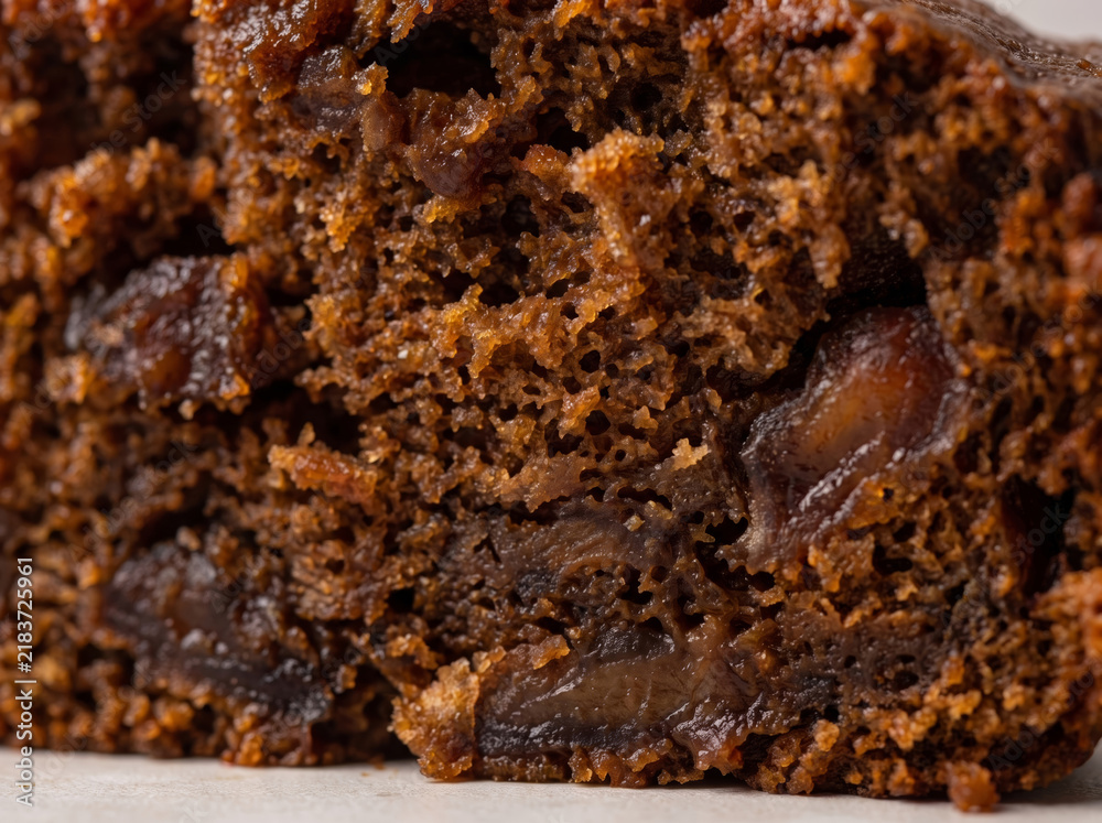 Fototapeta premium Macro shot of moist textured fruitcake crumb with dark dried fruit pieces