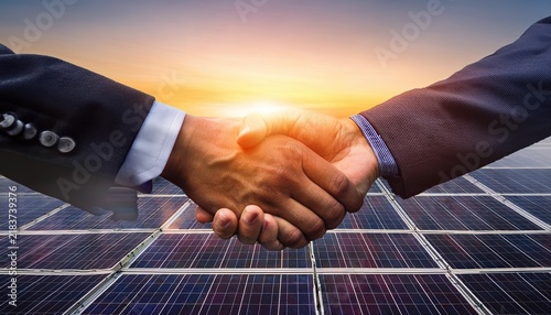 renewable energy partnership on solar farm at sunrise with business handshake