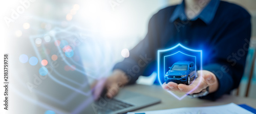 auto insurance policy,vehicle protection,safety coverage,shield guard,financial business and technology concept.Businessman holding blue car with glowing virtual shield guard icon on laptop background
