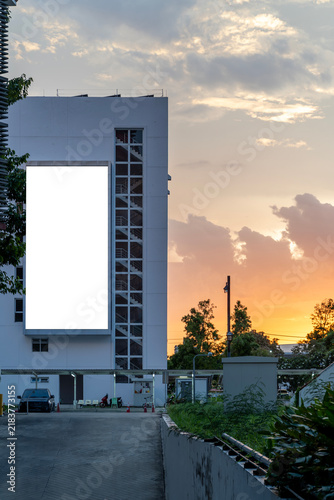 White building stands tall at sunset's glow. Sky paints orange and pink behind clouds.