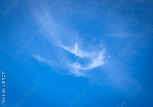 Soft white cirrus cloud on vibrant blue sky background with copy space.