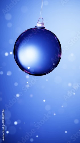 Hanging blue Christmas bauble with soft bokeh vertical loop