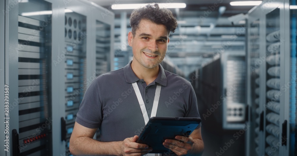 Fototapeta premium In Modern Data Center, IT Specialist Operates Digital Tablet in Server Room Corridor. Mobile Cloud Management and System Diagnostics Ensure Seamless Server Infrastructure Operation. Portrait.