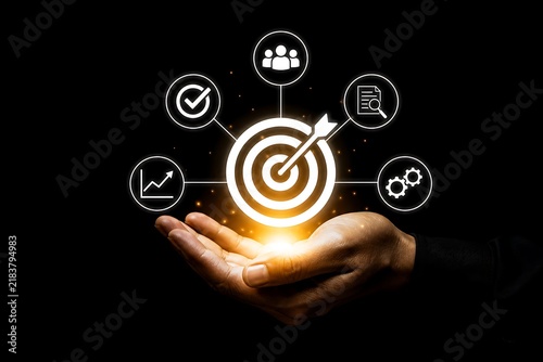 Hand holding target with icons symbolizing business goals and teamwork