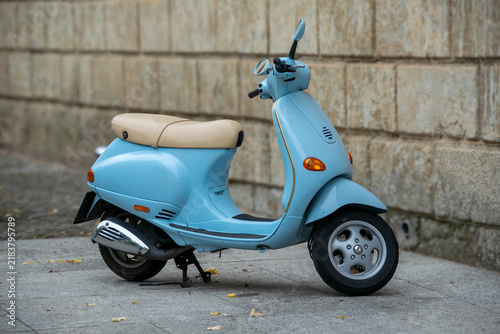 Blue scooter parked beside a stone wall