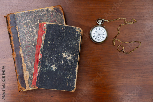 Foto Old vintage books with worn covers and antique pocket watch on wooden table