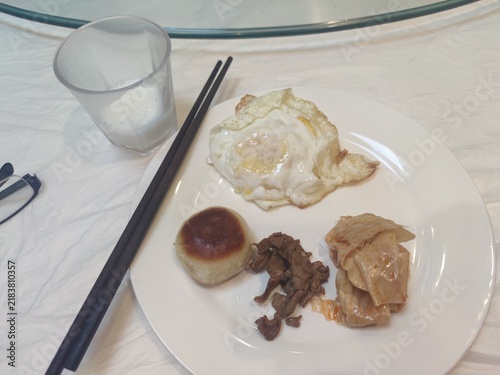 Foto Chinese breakfast plate with fried egg, beef, steamed bun and dumpling on white