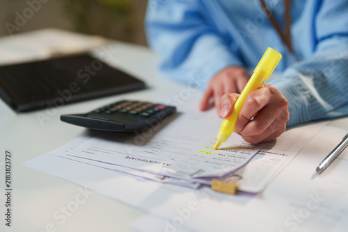 Fotografie Auditor highlighting deductible expenses on an itemized receipt and tax certific