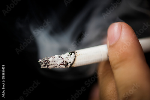 Foto Close Up of Hand Holding Burning Cigarette With Smoke