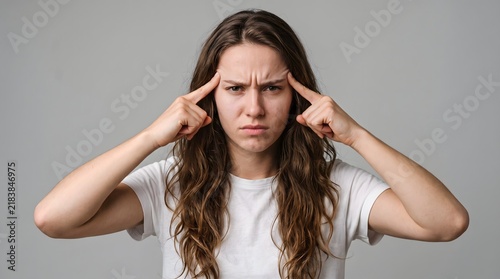 Young woman with long curly hair looking stressed and frustrated while touching her temples with both hands