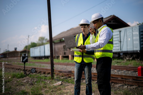Fotografie Two engineers in hard hats and safety vests inspecting train tracks outdoors