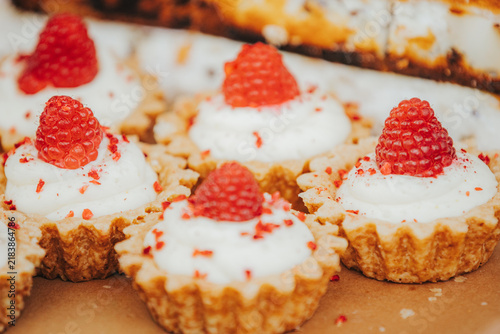 Canvastavla Miniature raspberry tarts with whipped cream and red sprinkles arranged on a bro