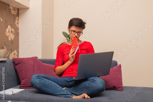 Bild auf Leinwand Person sitting on couch at home using laptop and holding a notebook while deep i
