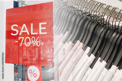 Принти на полотні Red seventy percent sale sign and clothing hangers in fashion retail background