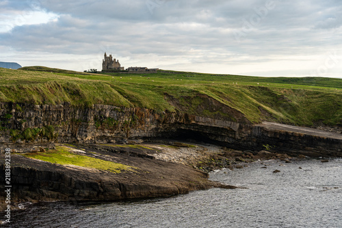 Foto Ancient castle ruins perched on green cliffs overlooking the Irish sea