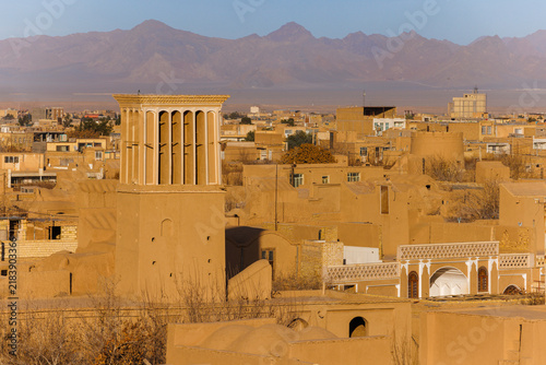 Traditional adobe houses around Narin Castle in Meybod, Iran. The historic earthen architecture of an arid desert settlement. A windcatcher against the backdrop of mountains