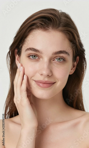 caucasian woman brown hair light green eyes posing gentle touch cheek smiling softly soft diffused studio lighting