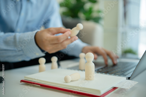 Canvastavla Business professional removing wooden employee figure beside laptop for workforce restructuring layoff decisions downsizing talent review and human resource planning