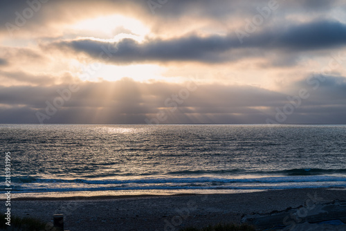 Quadro su tela Beautiful sunbeams breaking through dark clouds over the sea at a sandy beach in Klitmoller