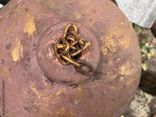 Top view close up of a rusted old gas cylinder tank valve with a metal chain