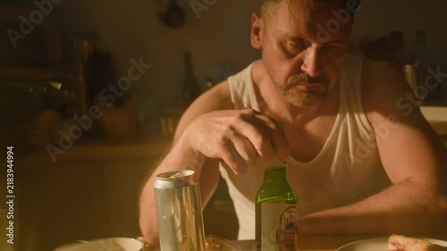 Middle aged Caucasian man drinking beer from bottle while struggling with alcohol abuse. Useful for mental health campaigns, addiction recovery programs, social awareness projects