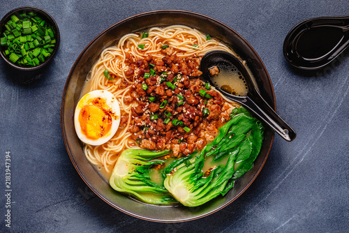 A bowl of noodles with minced meat, egg, and bok choy.