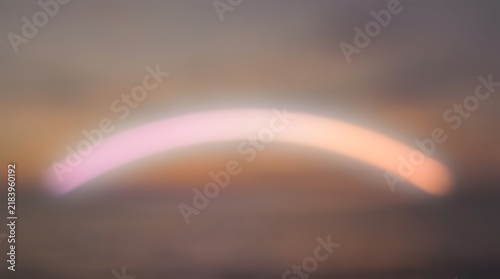 Soft pink and orange curved light streaks against a blurry sunset-like background