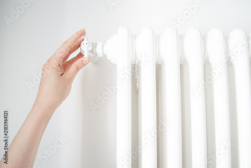 Obraz na plátně A woman hand adjusts the heat level using the knob on a radiator in a central heating system