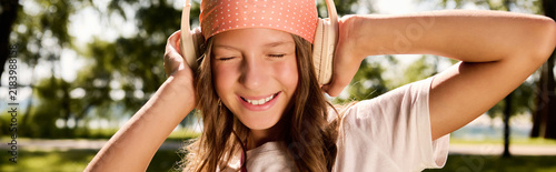 Canvastavla A joyful moments of a girl in headphones in a sunny park on a happy day