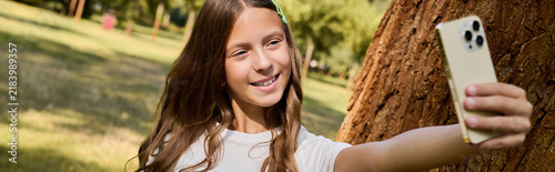 Canvastavla Bright smile of a happy girl enjoying a sunny day and taking selfie in the park