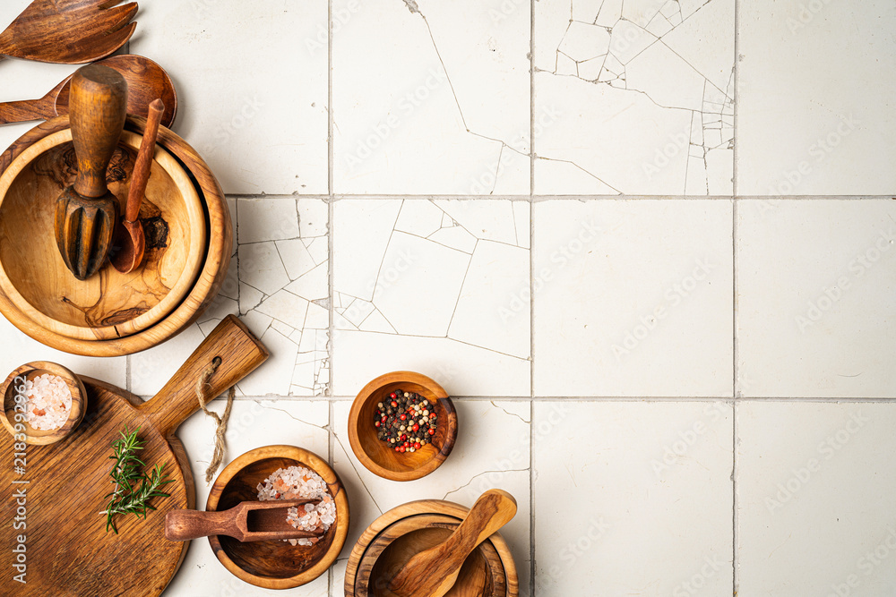 Obraz premium Old wooden kitchen utensils or cooking tools and bowls on white tile background, top view, flat lay. Kitchenware collection with copy space. Cooking background.