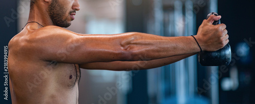 Obraz na plátně Focused Male Athlete Training With Kettlebell, Showing Strength And Determination At Modern Gym, Engaging In Workout Routine