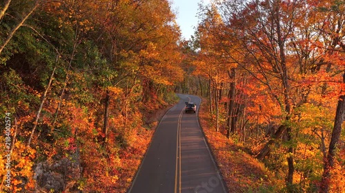 Car driving on mountain pass road between dense woods in seasonal colors in North Carolina. Blue Ridge Parkway in fall season.