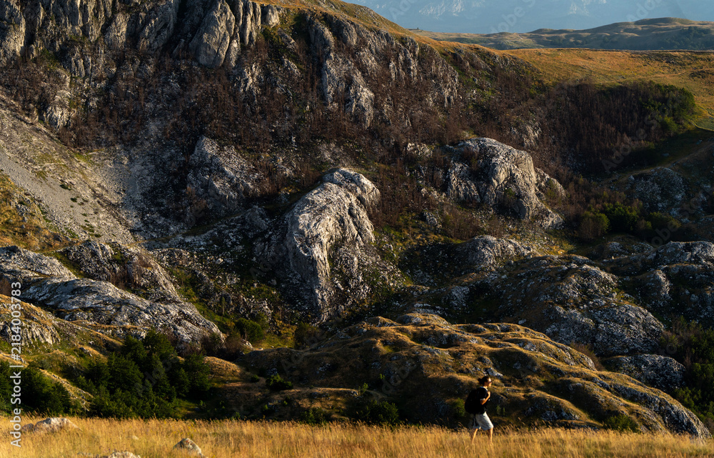 Obraz premium Female traveler walking on green hill slope, admiring epic landscape view. Small person big nature concept