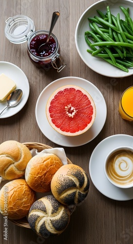 Top view flat lay of a hearty breakfast table with fresh bread rolls and grapefruit