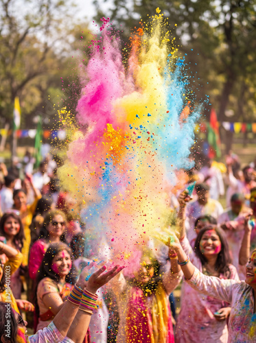 Joyful crowd celebrating holi festival throwing vibrant gulal powder in sunlight.