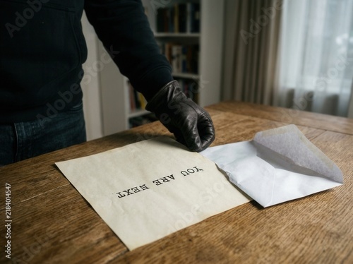 Obraz na płótnie Sinister Gloved Hand Places Threatening Note On Table