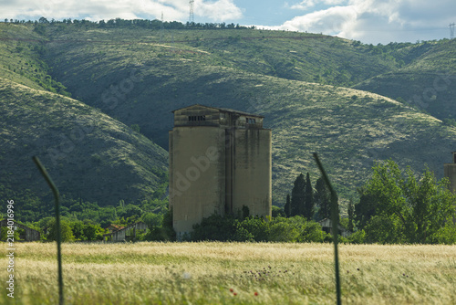 Abandoned Grain Silo in Rural Valley With Rolling Hills and Golden Field at Sunset