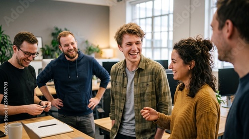 Diverse group of young professionals laughing and collaborating in a modern office environment