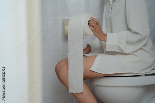 Canvas Print Constipation and diarrhea concept, woman sitting on toilet holding tissue paper