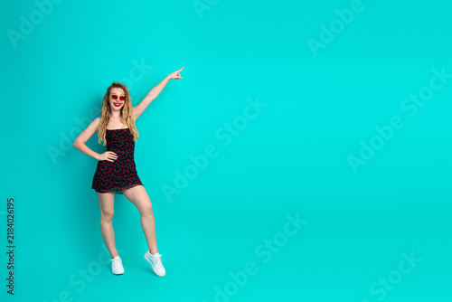 Fotografía Young stylish woman in a floral dress poses with teal background smiling and poi