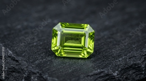 Emerald cut peridot gemstone on dark slate background, vibrant green gem, luxury jewelry stone