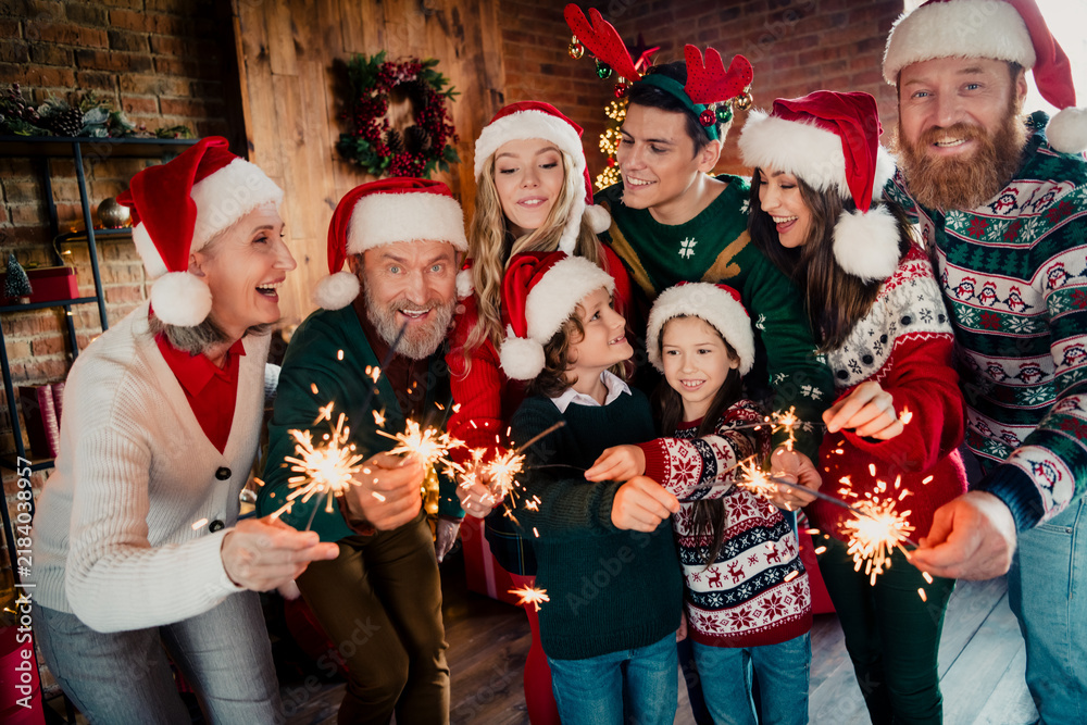 Fototapeta premium Multi-generation family celebrating Christmas with sparklers and Santa hats in a cozy holiday gathering