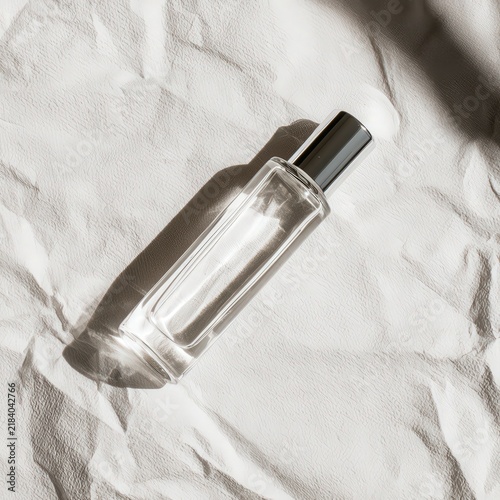 Clear glass bottle with metallic cap on textured white surface