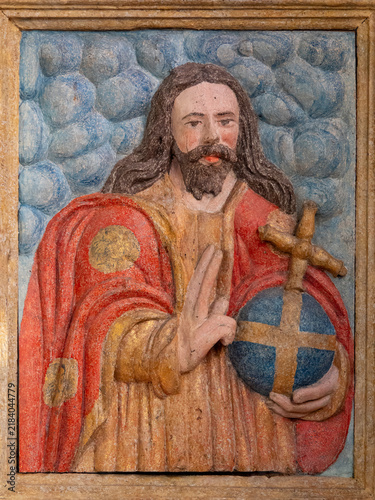 Фотография A polychrome relief depicts Jesus Christ holding a globus cruciger while raising his right hand